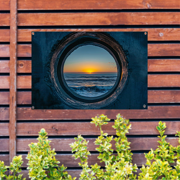 Zonsondergang door een ronde opening aan zee tuinposter