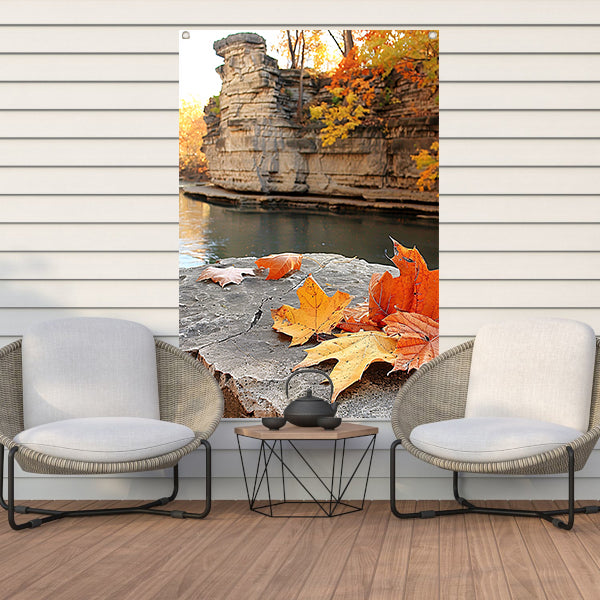 Herfstbladeren langs de rivier bij rotsen   tuinposter